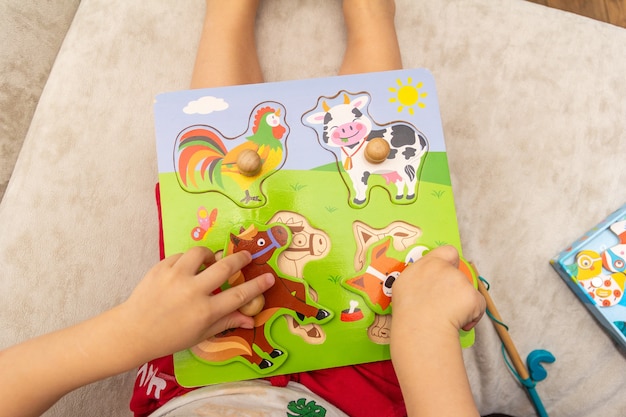 A child plays with wooden puzzles with animals