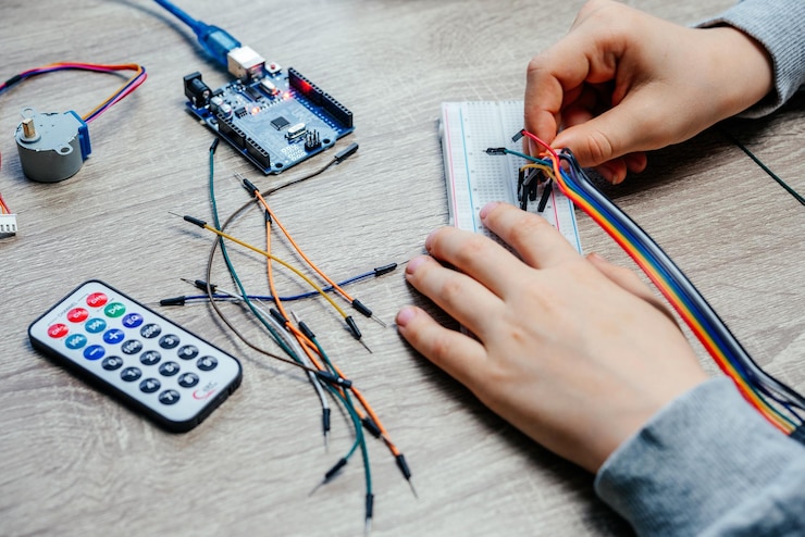 फोटो a child plugging cables to sensor chips while learning arduino coding and robotics