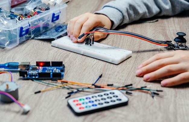 A child plugging cables to sensor chips while learning arduino coding and robotics