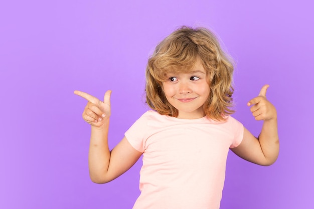 Child pointing away on isolated studio background kid with index finger pointing away on copyspace