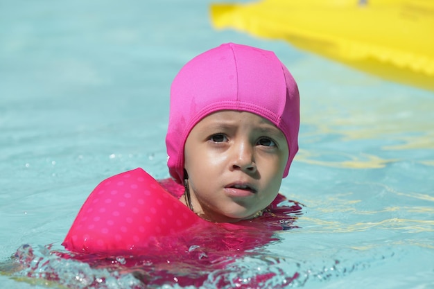 Foto bambino in piscina con galleggiante rosa con acqua blu