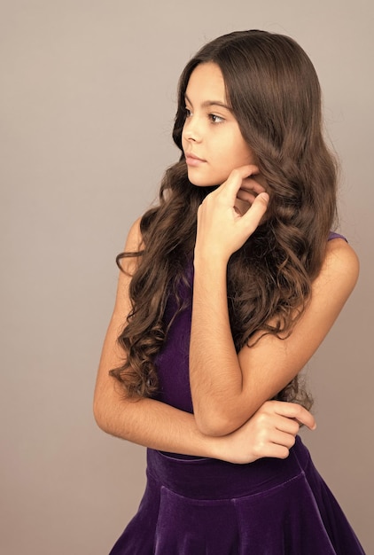 Child portrait with long frizzy hair touch her face skin beauty