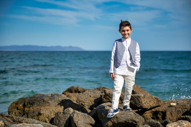 Child poses on rocks with sea in background