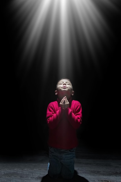 A Child praying spiritually to God on a black background