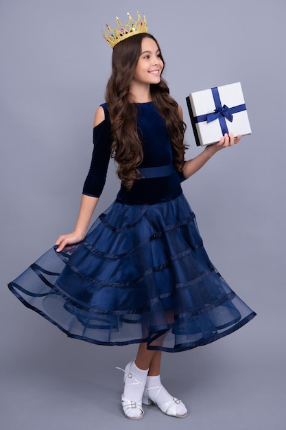 Child princess in crown wear ball dress on birthday party full length Teenager child with gift box Present for holidays Happy birthday Valentines day