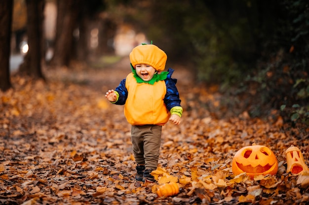 Child in pumpkin costume exploring park at Helloween