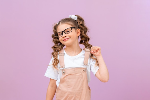 Child on a purple background. a girl with curly hair and glasses is smiling.