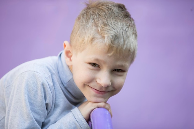 Child on a purple background Little blond boy smiles