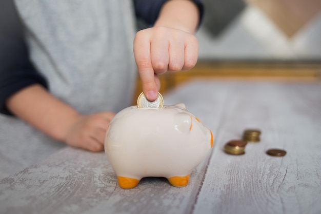 Child putting a coin into piggy bank