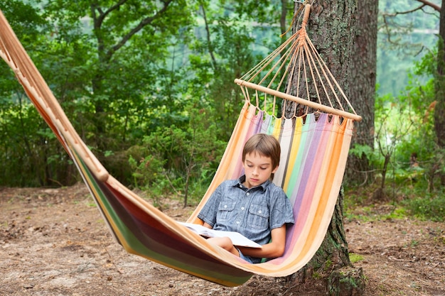 Child reading book in hammock