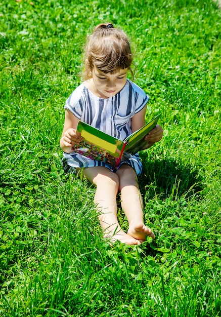 Child reading a book in nature.