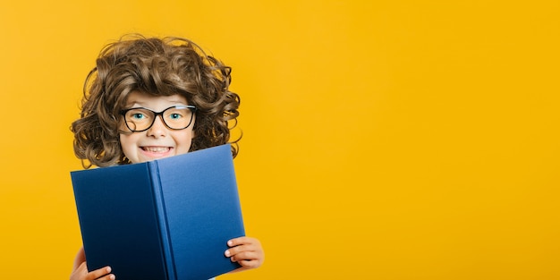 Child reads a book against a bright wall