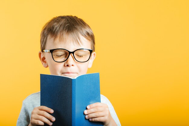 Child reads a book against a bright wall