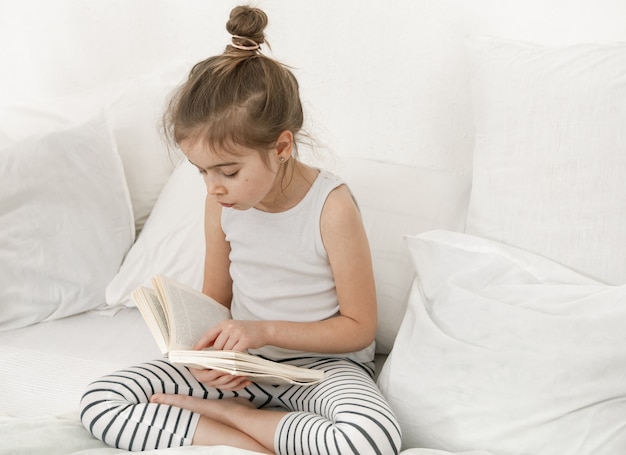 Il bambino legge un libro in pigiama. sviluppo del bambino e concetto di apprendimento.