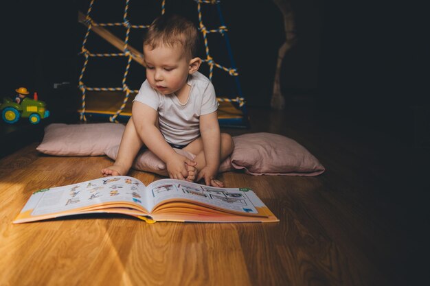 a child reads a book sitting on the floor at home