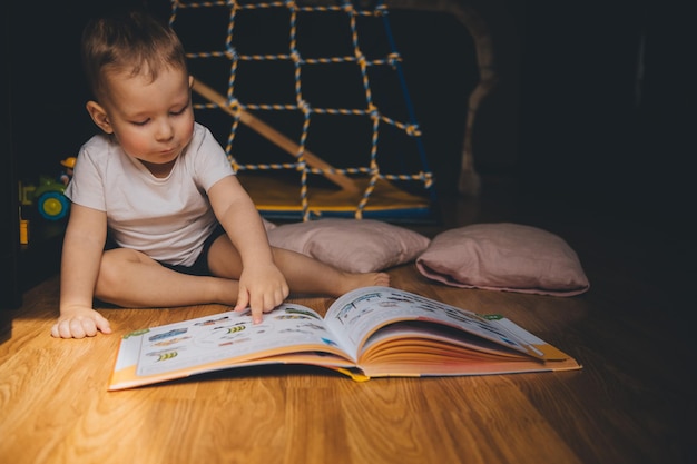 a child reads a book sitting on the floor at home