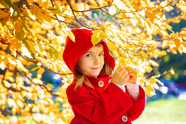 Child in a red coat with autumn leaves. Love autumn. Selective focus.