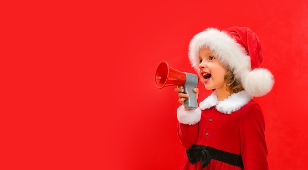 A child in a red Santa hat holds a megaphone in his hand and shouts slogans for Christmas