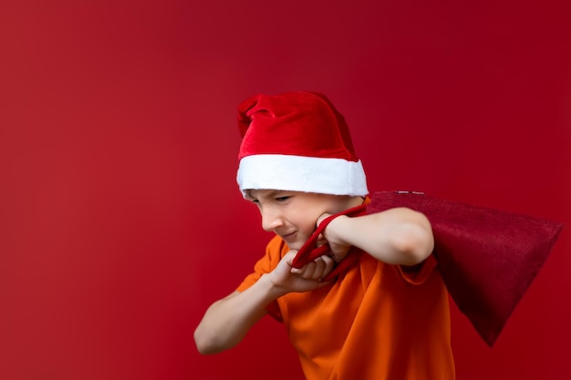 빨간 산타 모자를 쓴 아이가 어깨에 가방을 던졌습니다.