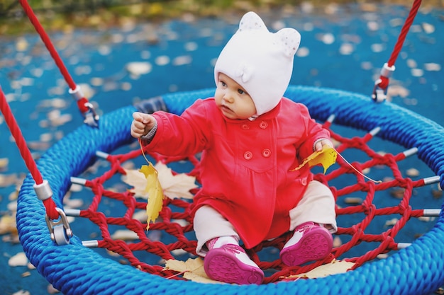 Child rides on swing with yellow autumn leaves