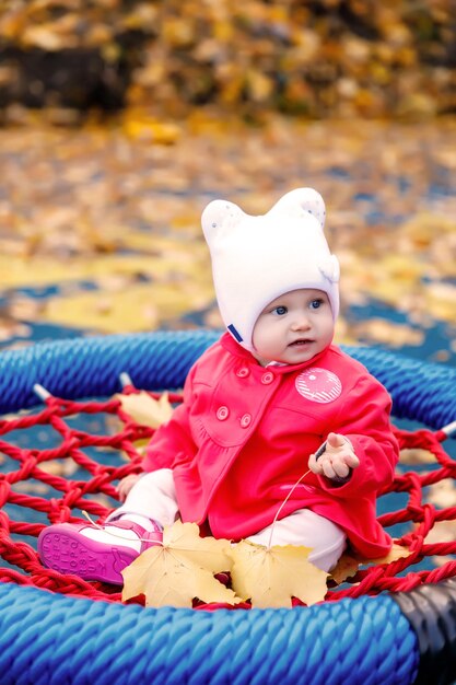 Photo child rides on swing with yellow autumn leaves