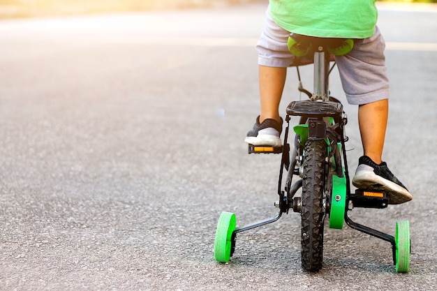 A Child riding a bike with training wheels.