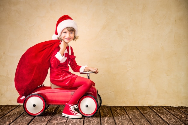 빨간 차를 타는 아이. 크리스마스 가방을 들고 아이입니다. 크리스마스 휴일 개념