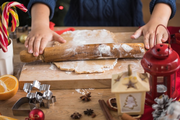 クリスマスのクッキーのために生地を展開する子供