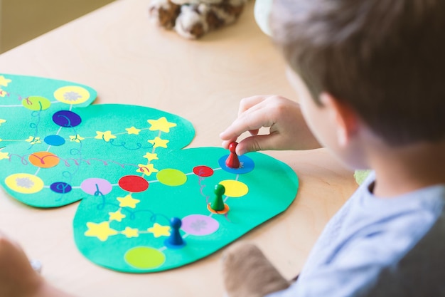 Child rolls the dice and moves the chip across the christmas playing field