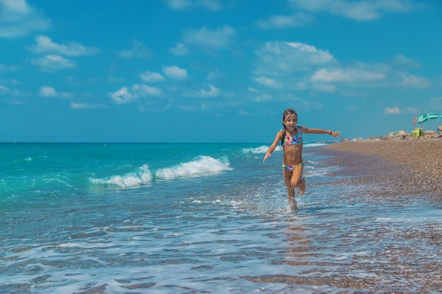 The child runs along the beach of the sea. Selective focus. Kid,