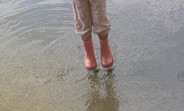 the child runs on puddles in rubber boots after a rain