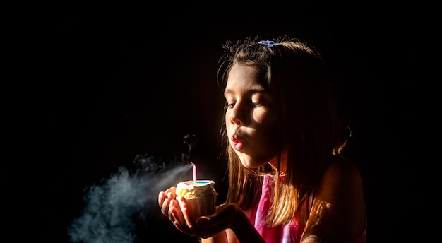 Child's birthday Kid girl makes a wish and blows out the candles on the birthday cake