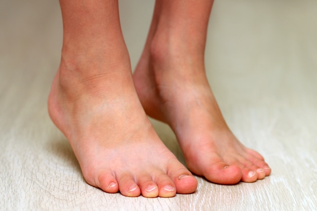 Child's feet on parquet laminate wooden texture floor close-up. Healthcare concept