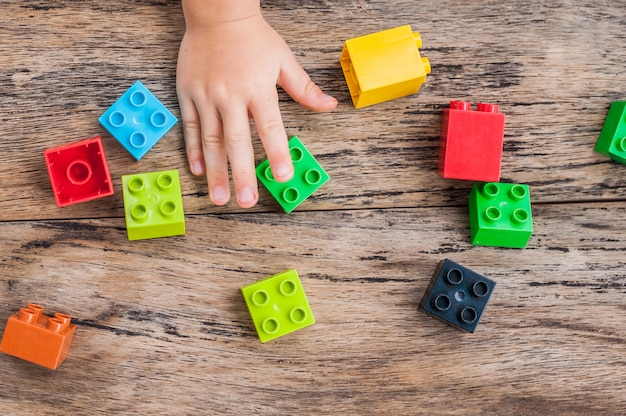 Child's hand and colorful toy building cubes
