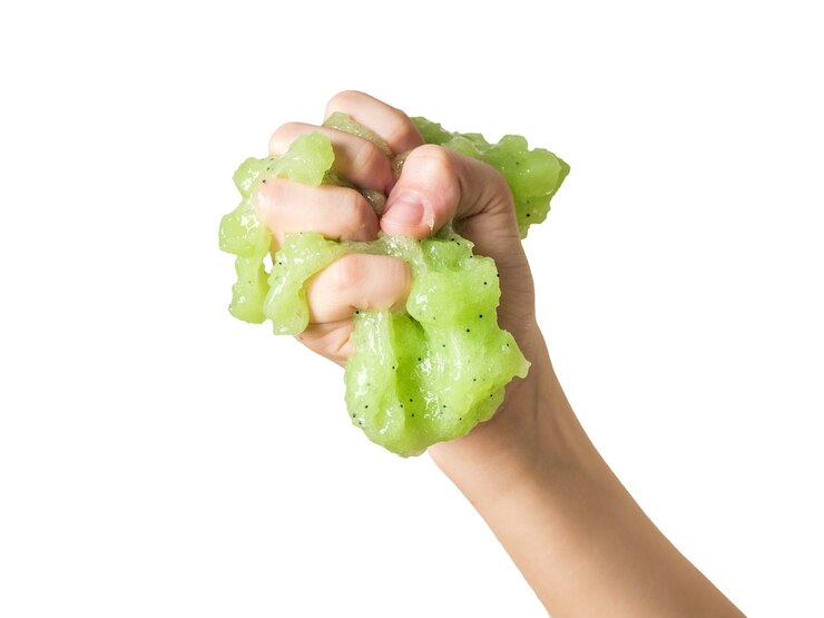 Photo a child's hand crushes a green lime isolated on a white background. popular children's game.
