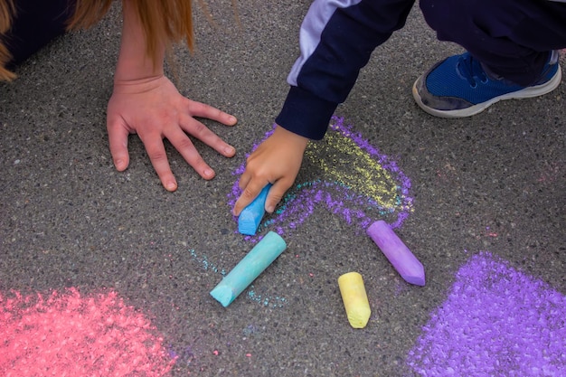 Child's hand draws hearts drawings chalk on asphalt