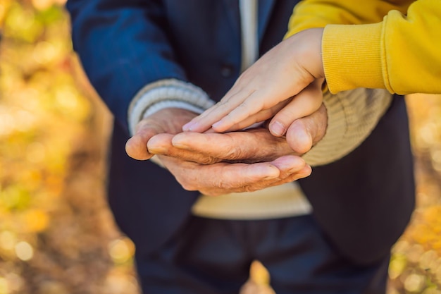 A child's hand holding the hand of an old man