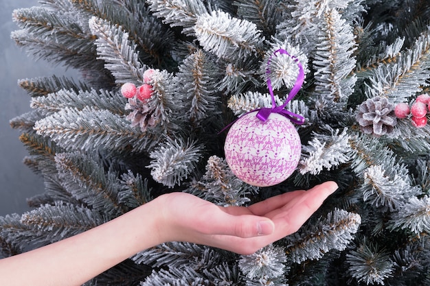 A child's hand insures a balloon toy from falling from a Christmas tree branch. decorative toy ball