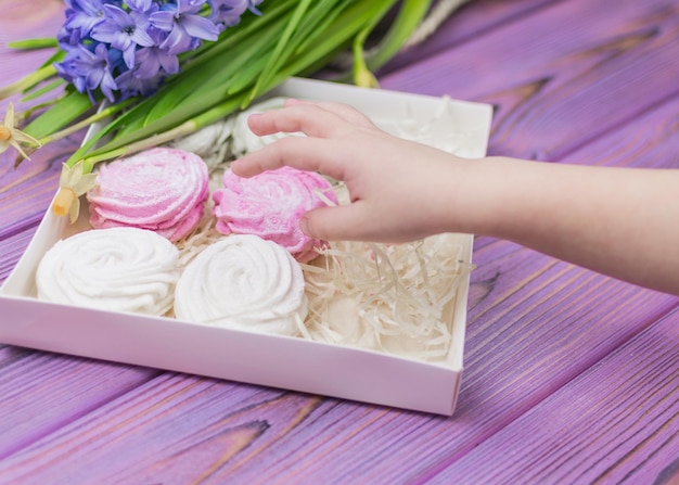 The child's hand reaches out for a candy box with a marshmallow zephyr