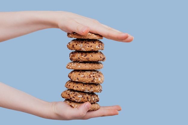 a child's hand with oat biscuits with seeds isolated on blue background,