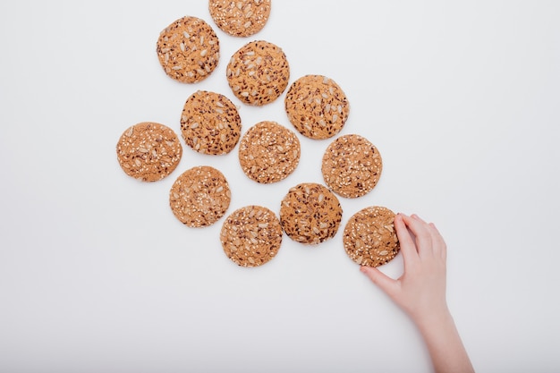 A child's hand with oat biscuits with seeds isolated on white background,