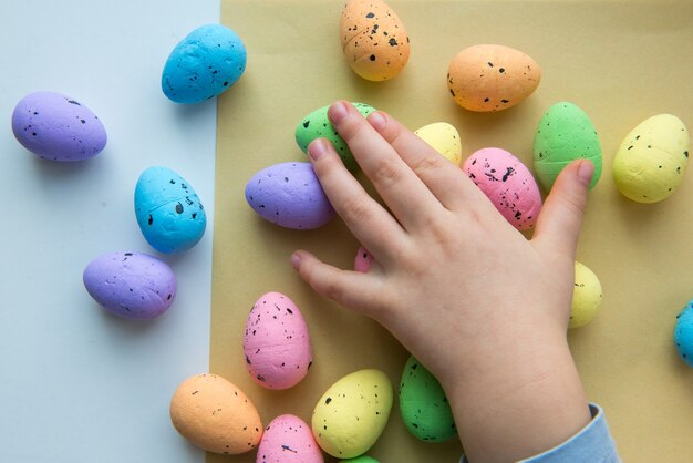 Child's hands are touching colorful Easter eggs