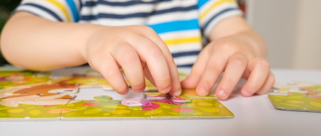 The child's hands close-up put together a picture of puzzles.