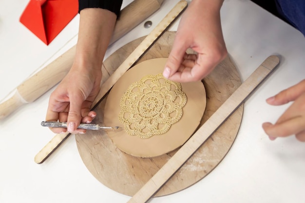 The child's hands make a clay plate Master class on making clay products