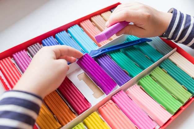 Mani del bambino con argilla colorata. bambino che gioca e crea giocattoli dalla plastilina, modellando la modellazione