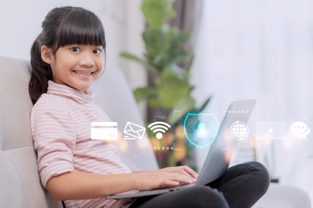 Child safety online little girl using laptop at home icon of\
internet blocking app on foreground
