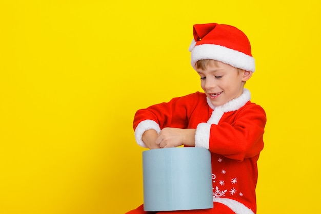 A child in Santa Claus clothes is trying to get a bag with gifts from a gift box