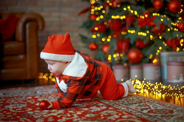 child in Santa Claus costume near a New Year tree on Christmas Eve Happy new year 2022 concept