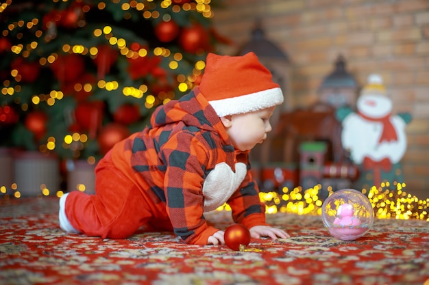 child in Santa Claus costume near a New Year tree on Christmas Eve Happy new year 2022 concept