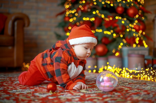 child in Santa Claus costume near a New Year tree on Christmas Eve Happy new year 2022 concept